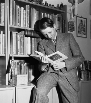 Skaugum, Asker 19490511 Prince Harald with the book Robin Hood in front of a bookcase …, 1949 (photo)