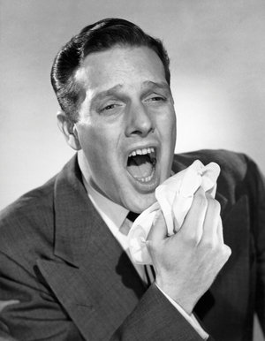 Close-up of a mid adult man sneezing