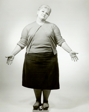 Woman weighing herself on scale (b/w photo)