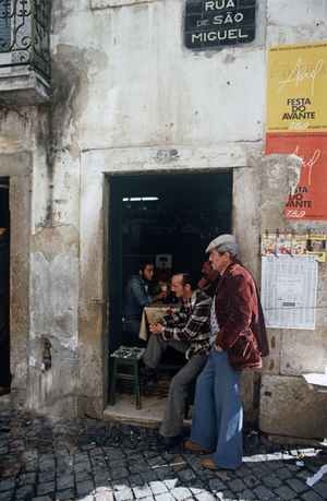 Workmen standing in doorway in cobbled stone street in Lisbon, Portugal (photo)