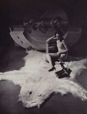 Woman sitting on a bearskin rug (b/w photo)
