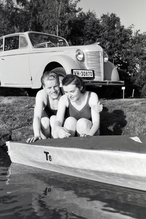 Young couple sitting in front of a boat at the river of a lake, Germany 1930s (b/w photo)