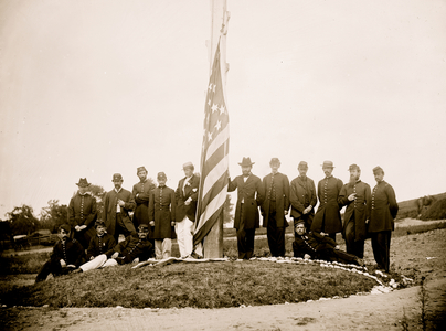 Washington, D.C. Signal Corps officers lowering flag at their camp near Georgetown; Gen Albert J. Myer, in civilian dress, at right of pole 1865 (photo)