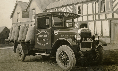 Truck carrying goods to market (b/w photo)