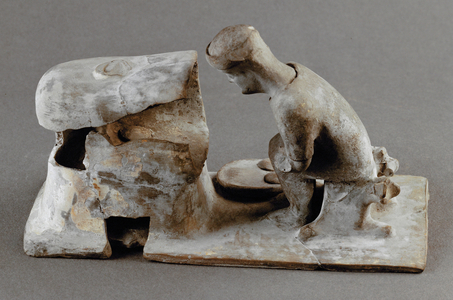 Baker squatting in front of his oven …