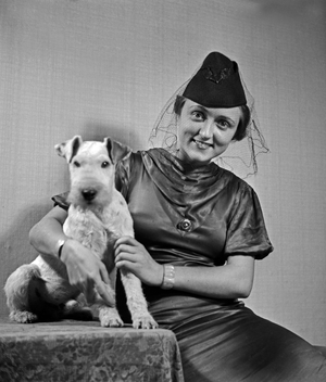 A lady and her dog pet at the photo studio in contemporary fashion, Germany 1930s (b/w photo)