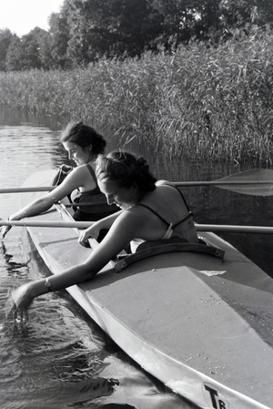 Two young women in bathing suits are paddling in a boat, Klepper T6 on a lake, Germany 1930s (b/w photo)