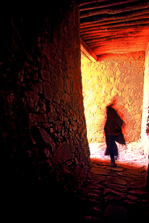 Though many monasteries have been destroyed, the Tibetans still maintain the ones that are left in their original condition. A monk walks through the stone inner passage of a monastery.  (photo)