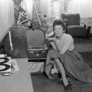 German schlager singer Melitta Berg sitting on the floor of a living room with a microphone and a reel to reel tape recorder, Germany 1950s