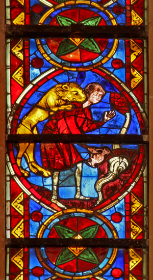 Window w213 depicting a scene from the life of St Thomas: a lion attacks the cupbearer as he collects water and removes his arm (stained glass)