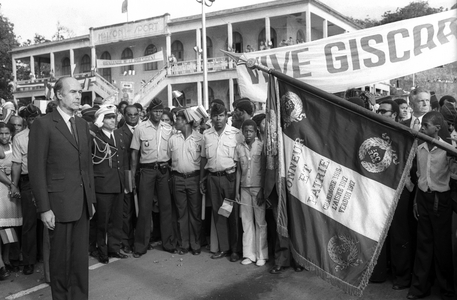 French President Valérie Giscard d'Estaing in front of the French flag upon arrival at Lamentin Airport in Fort de France during his trip to the West Indies to Guadeloupe on December 16, 1974 (b/w photo)