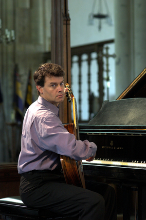Craig Ogden - portrait of the Australian guitarist playing a classical guitar, sitting in front of a piano in Orford Church at the Aldeburgh Festival, 1 June 2005