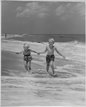 Boy and girl holding hands and running on the beach