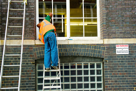 A man on a ladder repairing a window, London, England, UK  (photo)
