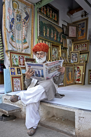 Shop owner reading a newspaper, Shrinathji Temple, Nathdwara, Rajasthan, India (photo)