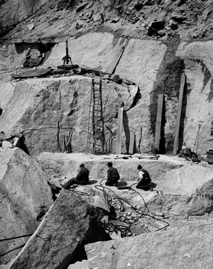 High angle view of three people sitting at granite quarry