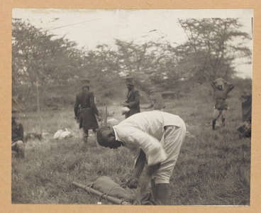 Photograph showing a young man in the foreground folding Theodore Roosevelt's tent, other men in the background. Taken during Roosevelt's trip to Africa, April 1910 (b/w photo)