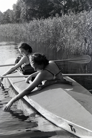 Two young women in bathing suits are paddling in a boat, Klepper T6 on a lake, Germany 1930s (b/w photo)