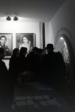 Visitors of the Leipziger Frühjahrsmesse at a Romanian stand with portraits of the Romanian King Michael I and his mother Elena of Greece, Germany 1941 (b/w photo)