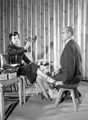 Woman shopping for shoes (b/w photo)