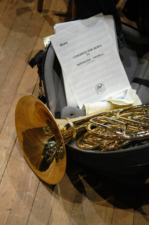 Horn in case next to a concerto score for horn