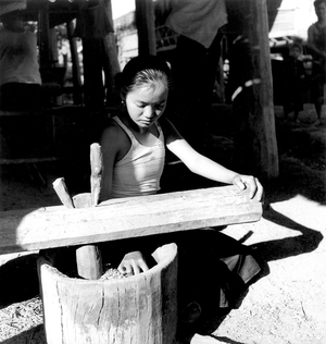 Laos: Meo population: a girl grindind grain, 1952-1955 (b/w photo)