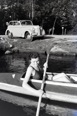 Young woman paddling in a boat on a lake near the river, Germany 1930s (b/w photo)
