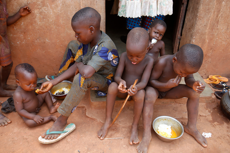 Children eating outside their home in a Zou province village, Benin, Africa (photo)