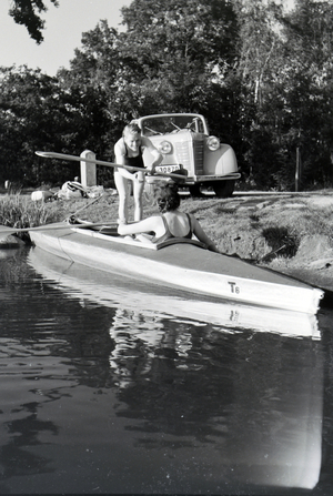 Young couple preparing for paddling in a boat on a lake, Germany 1930s (b/w photo)