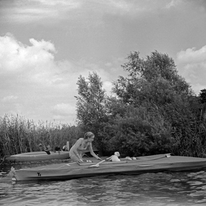 Advertising für a Klepper foldboat: a young woman playing with a puppy paddling on the shore of a lake, Germany 1930s (b/w photo)