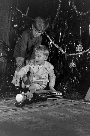 Two boys playing with the new model train under the christmas tree, Germany 1930s (b/w photo)
