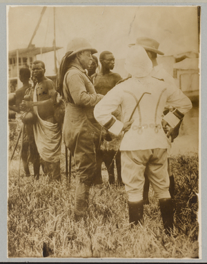 Theodore Roosevelt standing with mostly African men in traditional dress, April 9, 1910 (b/w photo)