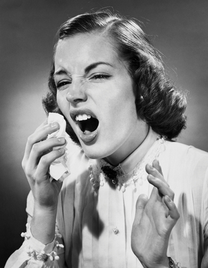 Close-up view of young woman sneezing