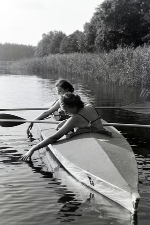 Two young women in bathing suits are paddling in a boat, Klepper T6 on a lake, Germany 1930s (b/w photo)