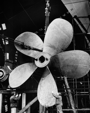 Two mature men working on the propeller of an industrial ship
