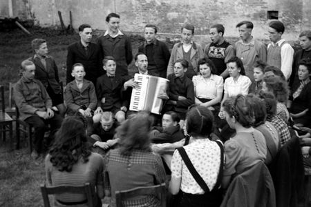 Priest Egon Voegler accompanying the yoith choir of Horka parish with his accordion, Germany 1949