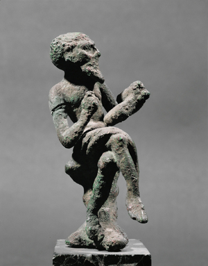 Grotesque figure of sitting hunchback holding rolls of papyrus …