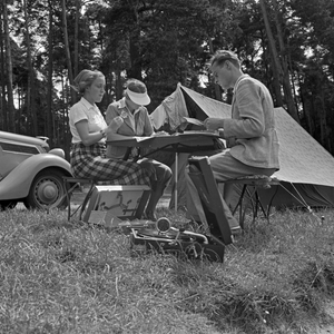 A man and two women sitting at a folding table in front of a tent, Germany 1930s (b/w photo)