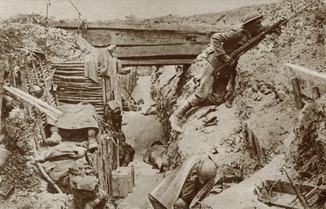 Soldier keeping watch whilst his comrades sleep in a trench during World War One.  From The Story of 25 Eventful Years in Pictures published 1935