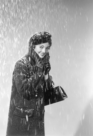Woman in winter coat and hat walks in the snow (b/w photo)