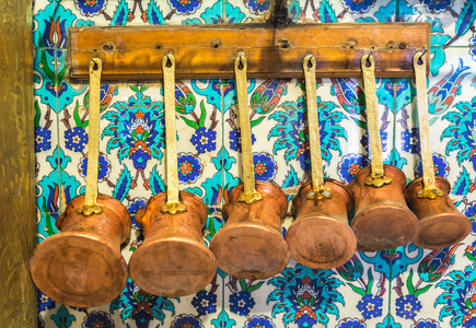 Istanbul, Turkey.  Various sized pots for preparing Turkish coffee hanging in a cafe kitchen.  Typical tiles on wall.