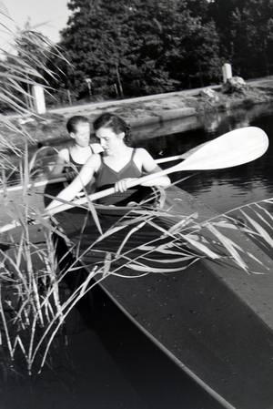 Young couple paddling in a boat on a lake near the river, Germany 1930s (b/w photo)