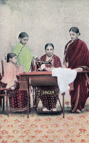 An Indian woman using a Singer sewing machine to sew a garment.