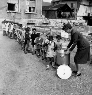 Woman of American Relief for France (association taking care of orphans in France after WW2) giving food to orphans in France 1945