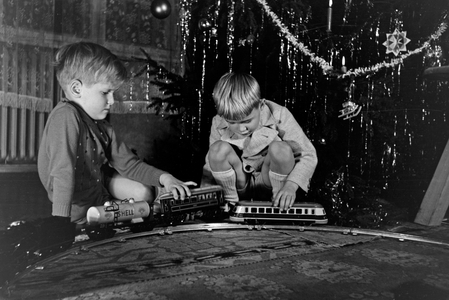 Two boys playing with the new model train under the christmas tree, Germany 1930s (b/w photo)