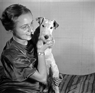 A lady and her dog pet at the photo studio in contemporary fashion, Germany 1930s (b/w photo)