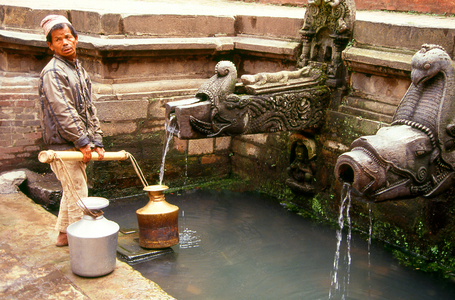 Nepal: A man fills his water pots at the Tusha Hiti, a well lined with a profusion of stone carvings in the Sundari Chowk or 'Courtyard of Beauty' within the Royal Palace, Patan, Kathmandu