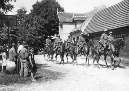 Cavalry patrol passes through a village (b/w photo)