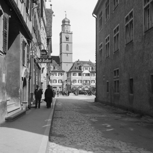 Business street with restaurant Ratskeller and the belfry of St Johannis minster at Bad Mergentheim, Germany 1930s (b/w photo)