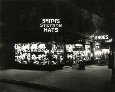 Lit up store fronts advertising Smith's Stetson Hats, Shoes, Liquors, c.1910-21 (b/w photo)